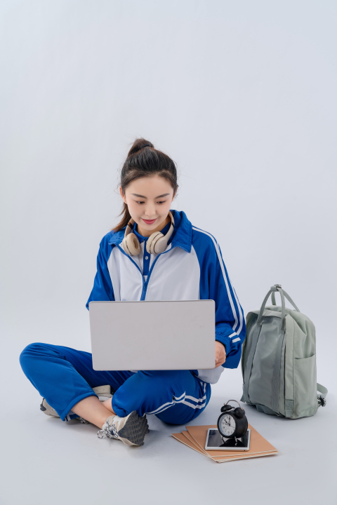 坐地上笔记本复习功课的女学生实拍图版权图片下载