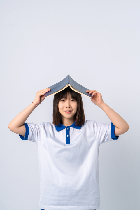 书在头顶的女学生实拍图版权图片下载