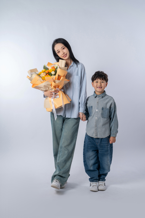 手抱鲜花领着儿子拍照的妈妈高清图版权图片下载