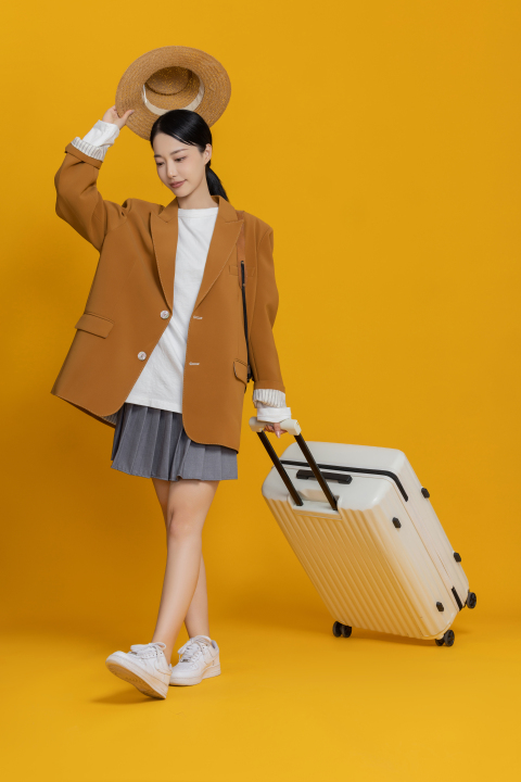 一只手举着帽子一只手拖行李箱女生高清图版权图片下载