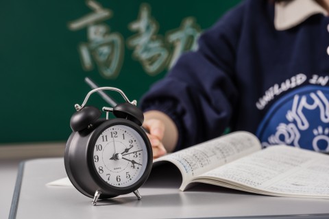 黑色闹钟和正在学习的学生高清图